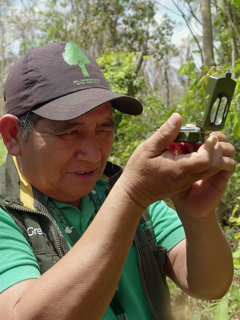 Monitor comunitario tomando un rumbo con brújula en el bosque