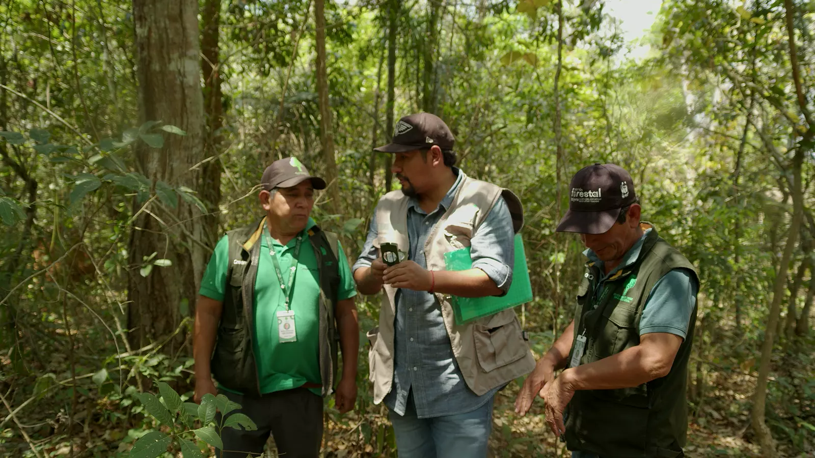 Monitores en el bosque registrando datos con brújula y planilla